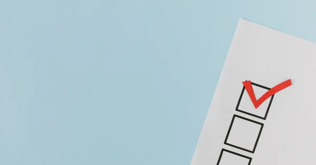 Checkliste auf weißem Papier mit einem roten Haken in einem Ankreuzfeld vor hellblauem Hintergrund