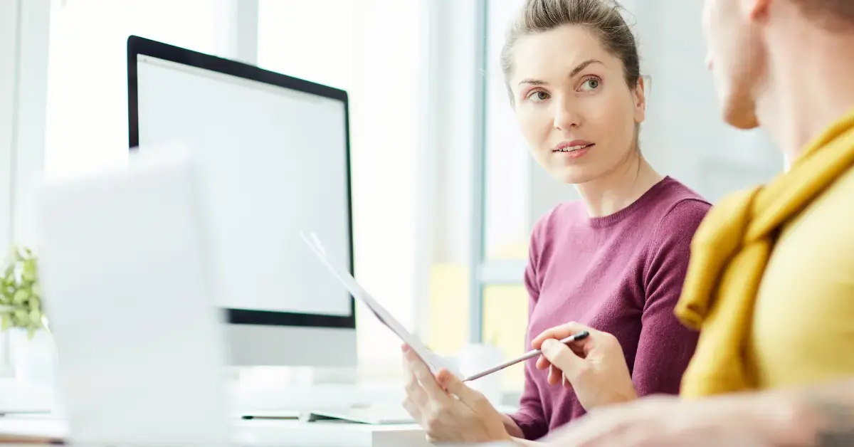 Zwei Kollegen prüfen gemeinsam Dokumente am Computer als Entscheidungshilfe für klinische Leistungsstudien unter der IVDR.