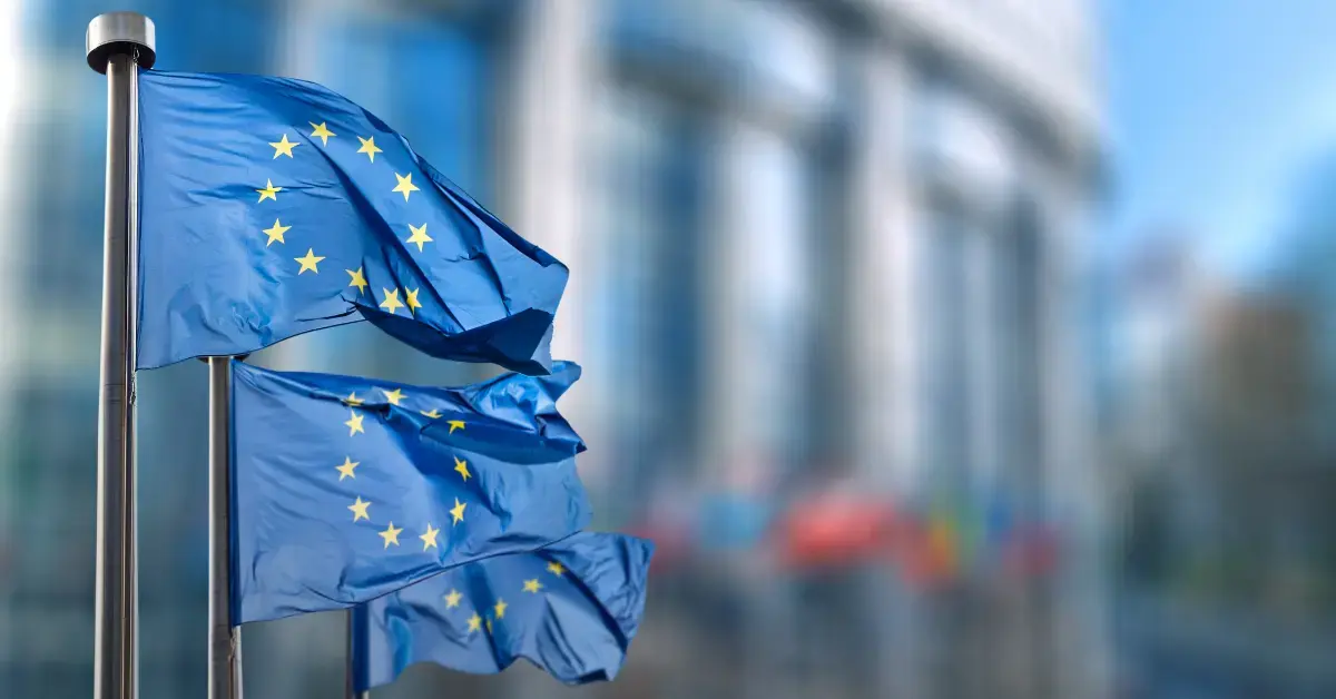 EU-Flaggen vor einem europäischen Regierungsgebäude als Symbol für Post-Market Surveillance (PMS), neue EU-Leitlinien, MDR-/IVDR-Compliance und regulatorische Anforderungen für Medizinprodukte.