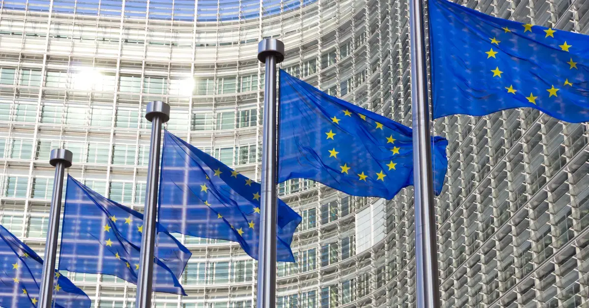 EU-Flaggen vor einem Gebäude der Europäischen Union als Symbol für neue regulatorische Anforderungen und Gesetzesänderungen für Medizinprodukte und In-vitro-Diagnostika.