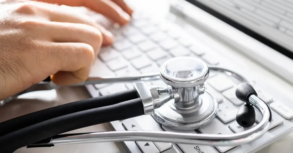 Stethoskop auf einer Computertastatur neben einer arbeitenden Person – Symbol für die Rolle von Medical Experts bei der klinischen Bewertung und regulatorischen Compliance von Medizinprodukten.