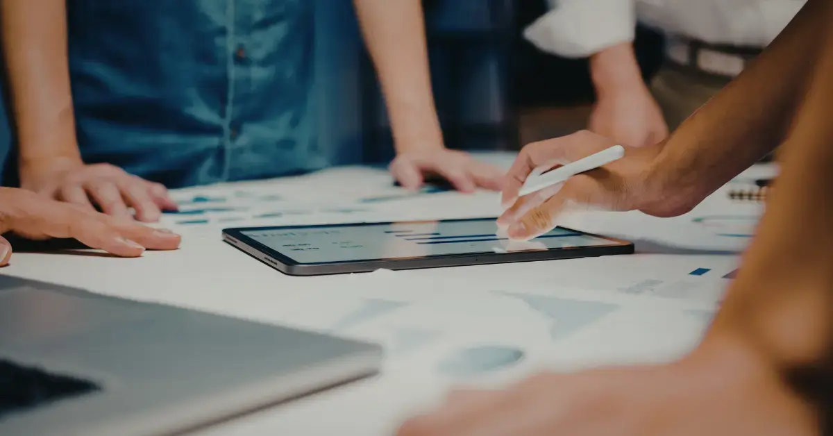 Team arbeitet gemeinsam an einem digitalen Dashboard auf einem Tablet – Symbol für die erfolgreiche Integration von RIM-Systemen und regulatorischer Expertise in der Medizintechnik.