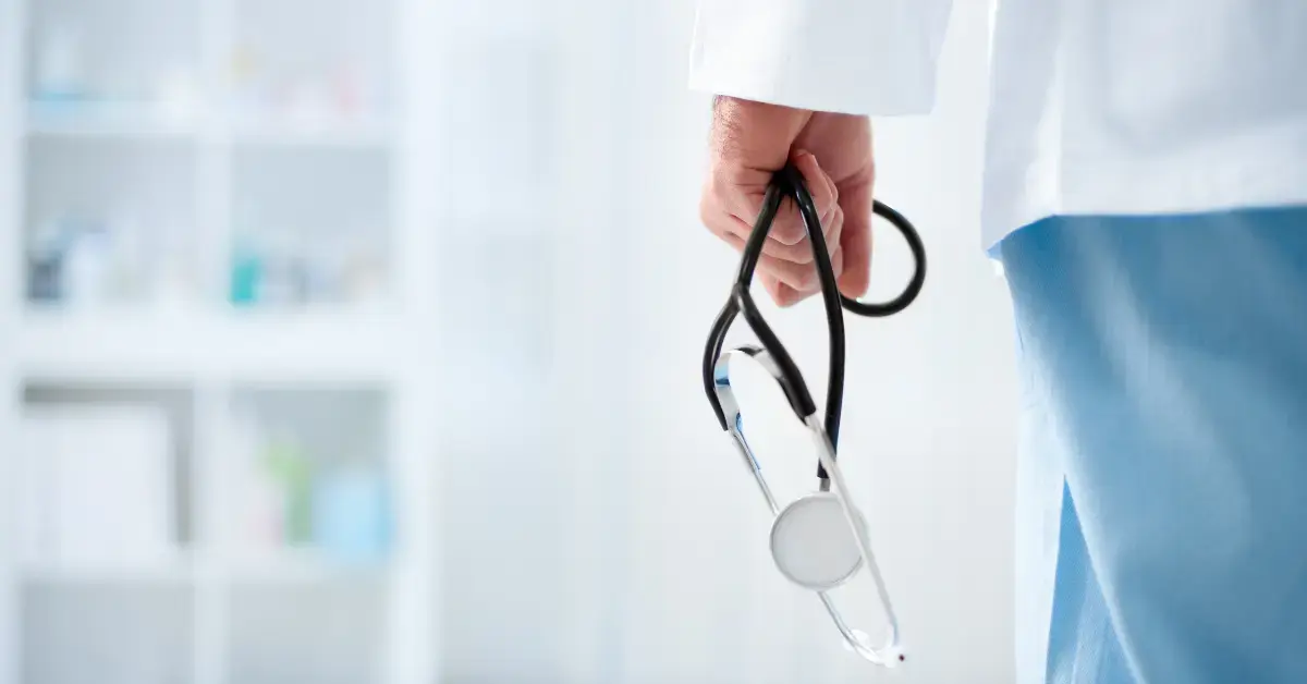 Eine Person aus dem medizinischen Bereich hält ein Stethoskop, symbolisch für klinische Praxis und medizinische Forschung im Krankenhausumfeld.